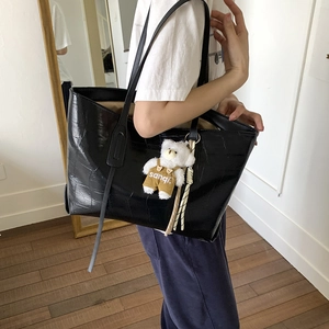 Black crocodile embossed tote bag with teddy bear charm shown in a mirror selfie