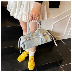 Detail of light blue denim baguette bag with large bow and metallic belt buckle detail