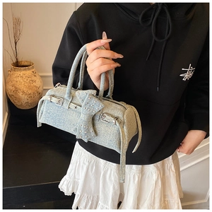 Detail of light blue denim Boston bag with silver rivets and bow decoration