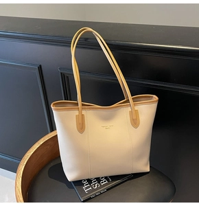 Detail of a minimalist beige tote bag with caramel trim on a sleek black stool
