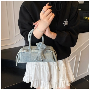 Detail of light blue denim pillow bag with large bow, silver studs and metal buckles
