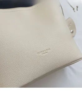 Close-up of beige lychee texture faux leather with hot-stamped DUOMI & BAG logo