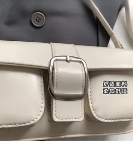 Close-up of cream shoulder bag featuring textured leather and a square silver buckle