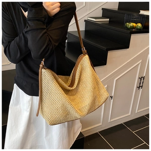 Détail du sac cabas en paille tissée avec anses en cuir marron et fermeture éclair