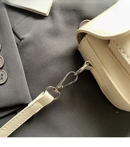 Detailed close-up of shiny silver metal hardware connecting the creamy white leather strap