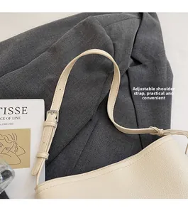 Detail view of off-white leather bucket bag with lychee texture and adjustable strap