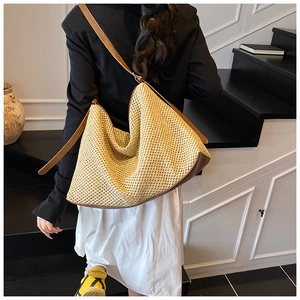 Détail du sac fourre-tout en paille tressée avec lanières en cuir marron et design