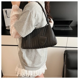 Detailed view of black woven shoulder bag with knotted strap and Intrecciato craft