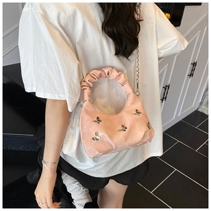 Détail du sac plissé en satin rose avec décorations papillon en métal et bandoulière chaîne