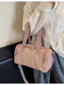 Pink nylon barrel travel bag with adjustable strap and textured fabric shown on a model