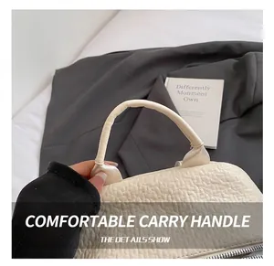 Gros plan d'un sac à main beige en cuir grainé avec détails de couture sur la poignée