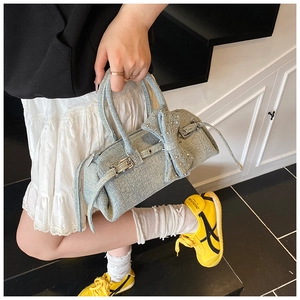 Close-up of light blue denim pillow bag featuring a large decorative bow and metal buckle