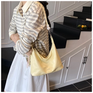 Detail view of cream crocodile-pattern bag featuring elegant pearl strap and chain