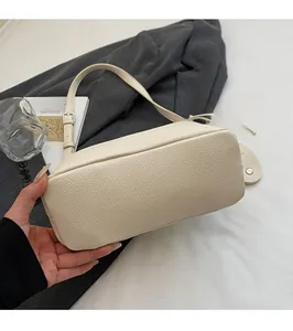 Detail of off-white lychee texture leather bucket bag with adjustable silver buckle strap