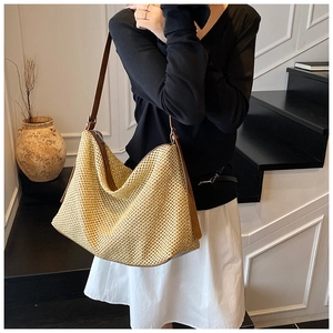 Détail d'un grand sac cabas tissé en paille beige avec bandoulière en cuir marron