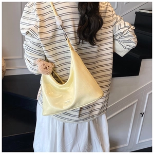 Pale yellow croissant bag with croc pattern and cute bear charm shown on a model