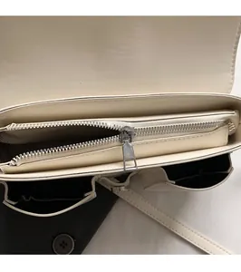 Detail of multi-compartment interior with smooth silver metal zipper on cream leather bag