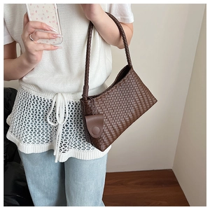 Detail of brown woven hobo bag with round coin purse charm and thick braided handle