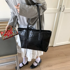 Detail of black crocodile texture tote bag with shoulder strap shown in a lifestyle scene