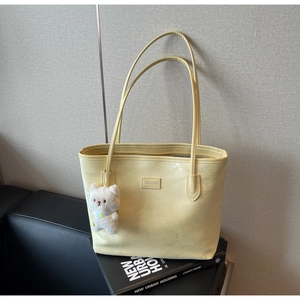 Detail of light yellow PU leather tote with bear charm and monogram pattern print