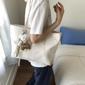 Detailed texture of white crocodile pattern tote bag with a cute bear plush keychain
