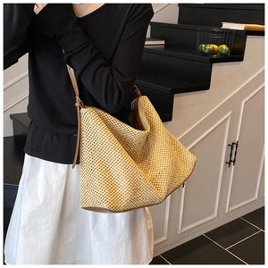 Gros plan sur un sac cabas en paille tissée avec lanières en simili cuir marron et maille