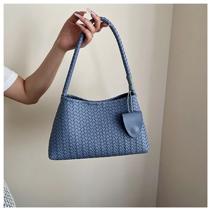 Detailed close-up of blue woven leather texture and handle on a minimalist hobo bag