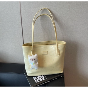 Macro shot of light yellow printed tote bag with plush bear charm on books