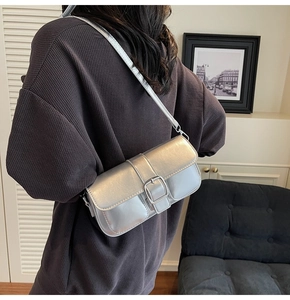Detail view of a silver metallic baguette bag with a square buckle and sleek shoulder strap