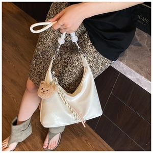 Close-up of white hobo bag with crocodile embossing, plush bear charm and silk scarf