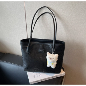 Detail of black PU tote bag with matte letter patterns and a plush cat charm