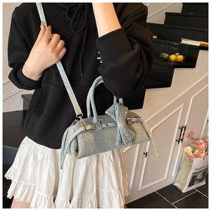Detail of light blue denim Boston bag featuring Y2K bow, silver rivets and belt buckles