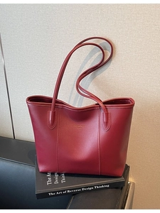 Vintage burgundy leather tote bag with gold lettering placed on an art book in a studio setting