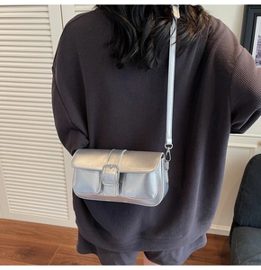 Rear view of a model wearing a stylish metallic silver crossbody bag with a square buckle