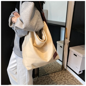 Side view of large off-white canvas tote bag with brown leather straps for daily commute