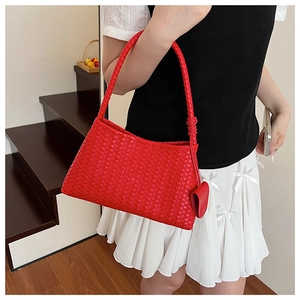 Detailed macro view of vibrant red woven leather handbag with heart charm accessory