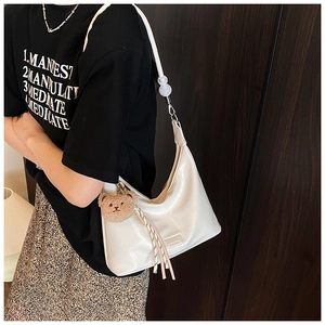 Close-up of white crocodile pattern shoulder bag with transparent beads and bear charm
