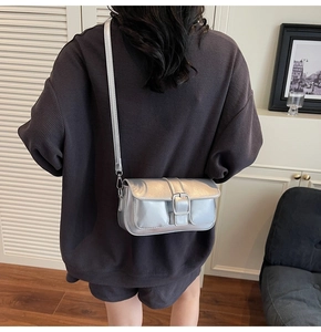 Silver metallic crossbody flap bag with square metal buckle shown on a female model