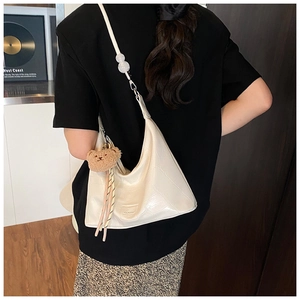 Detail of white crocodile pattern shoulder bag featuring pearl strap and bear pendant