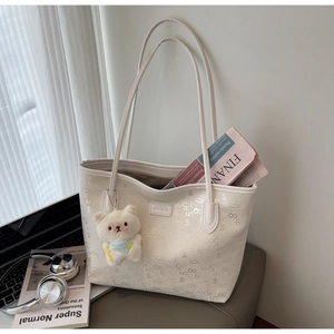 Detail of off-white tote bag with numeric pattern and cute teddy bear charm