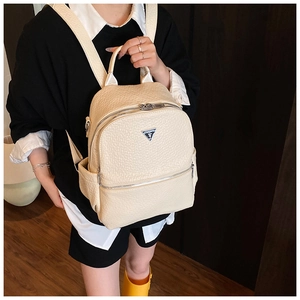 Vue de style de vie du sac à dos en cuir crème avec texture litchi et logo argenté