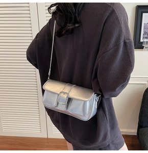 Close-up of a stylish silver rectangular crossbody bag with metallic finish on a model