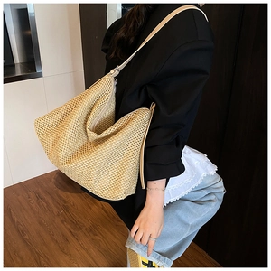 Détail d'un grand sac cabas en paille tissée avec bandoulière en cuir crème et fermeture éclair