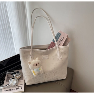 Detailed view of white monogram tote bag with cute plush cat pendant and brand plaque