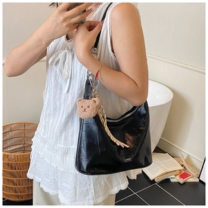Detail of black crocodile texture bag with bear charm and silver zipper accents
