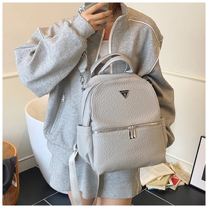 Vue latérale du sac à dos en cuir grainé gris sur un mannequin en tenue décontractée