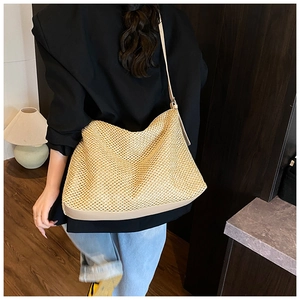 Detail of hand-woven straw tote bag with premium leather trim and hollow-out mesh texture