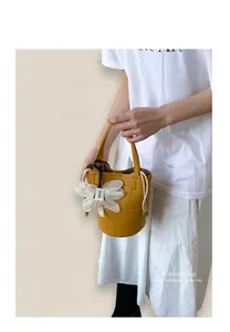 Detail of yellow lychee leather bucket bag with large white flower charm and drawstring