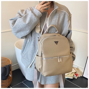 Sac à dos beige tendance porté par un mannequin avec logo métallique et poches