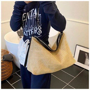 Détail du sac hobo en paille tressée montrant la bordure en cuir et la fermeture éclair